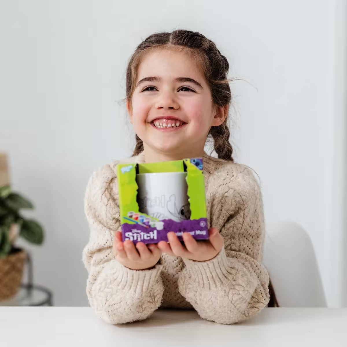Lachend meisje toont Totum Stitch verf je mok set, creatief cadeau en voor kinderen die graag dingen om te knutselen maken.
