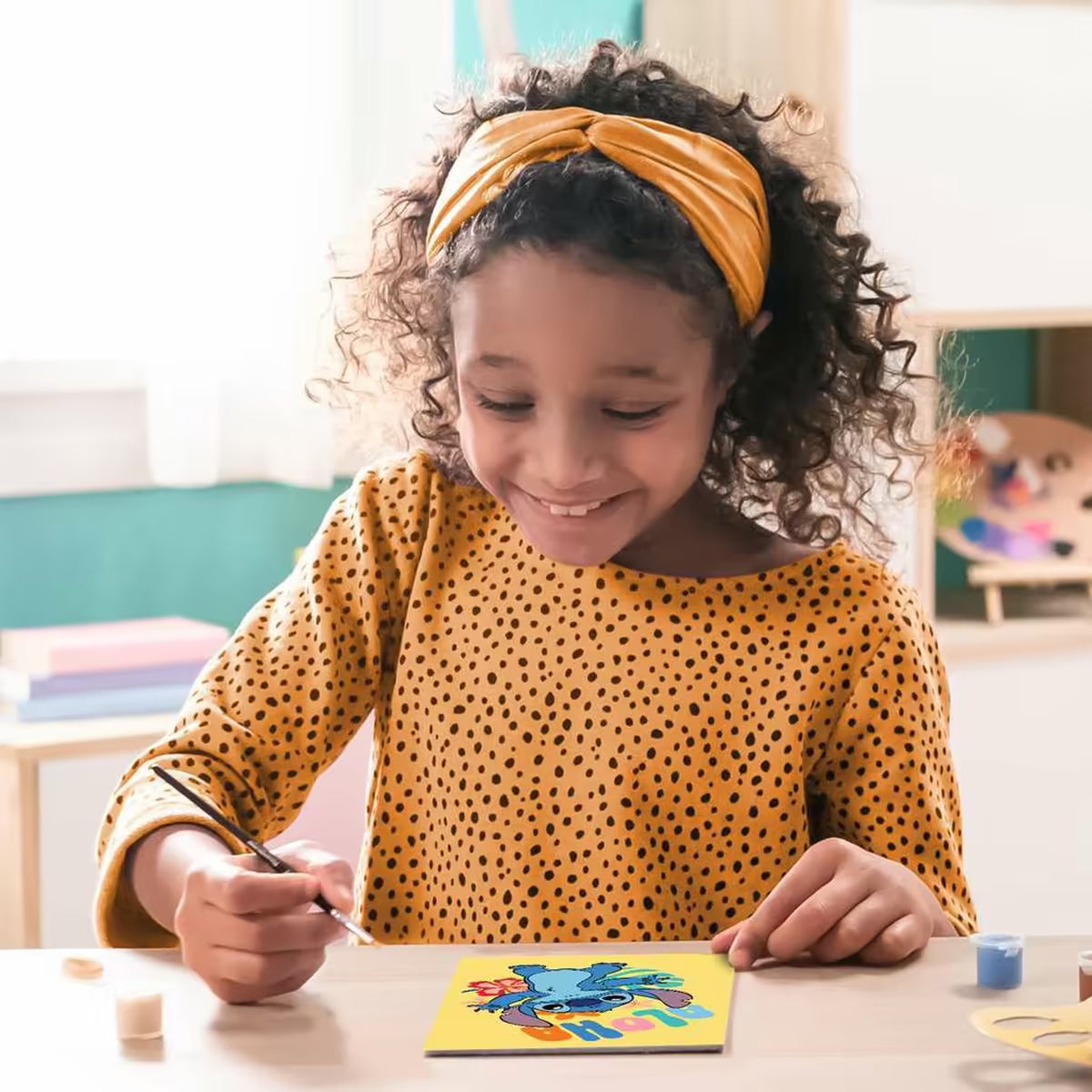 Kindvriendelijke foto van meisje dat vrolijk Disney Stitch schilderij maakt van Ravensburger, ideaal om te knutselen met kinderen.