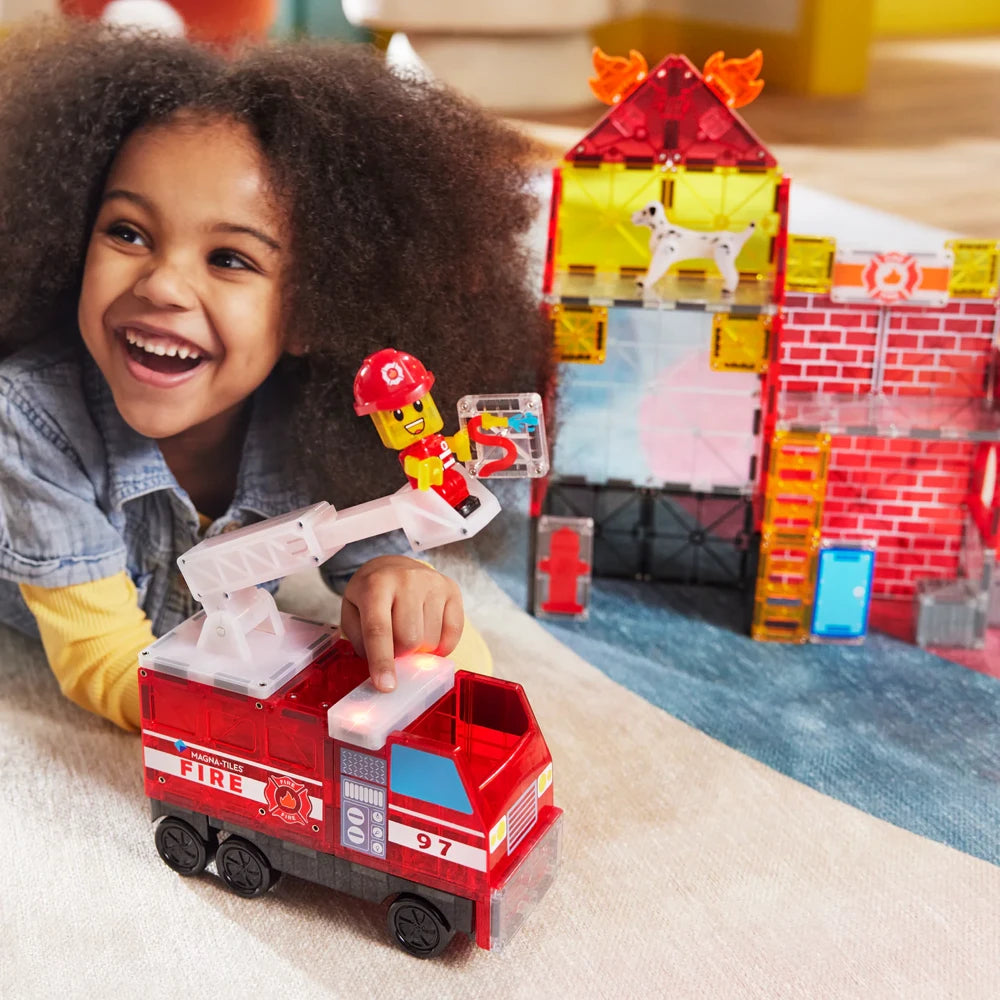 Lachend meisje speelt met brandweerauto en figuur uit de Magnetic Magna Tiles Fire Station speelset.