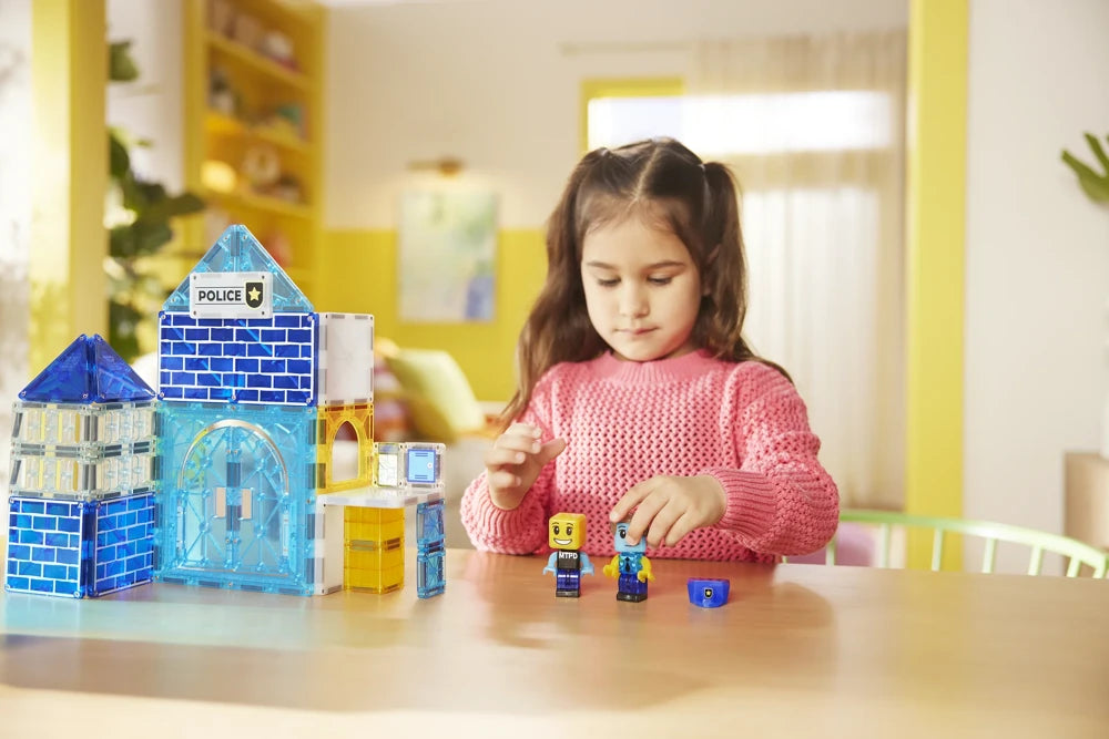 Meisje speelt aan tafel met magnetische politiefiguren en het blauwe Police Station van Magna Tiles MicroMags.