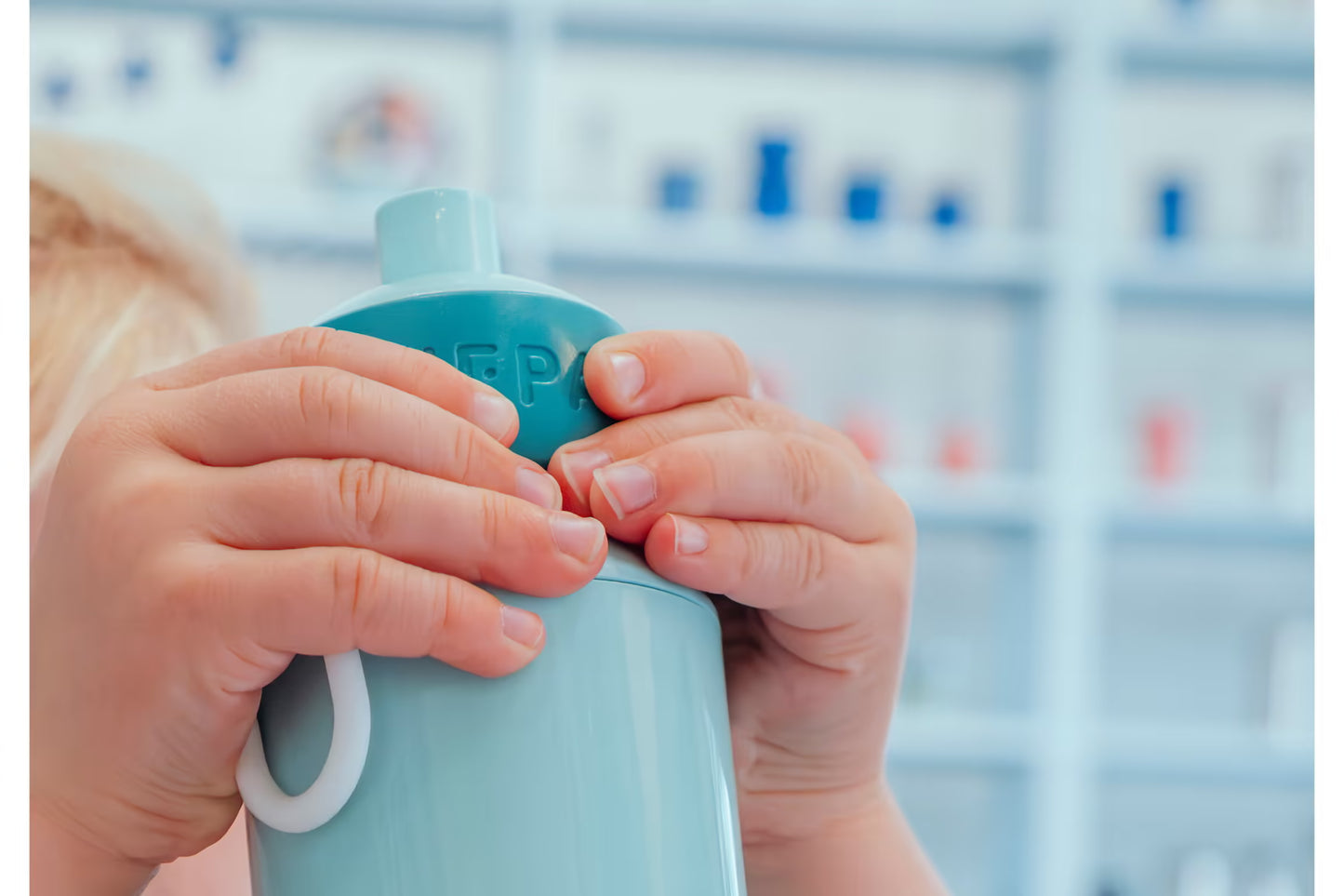 Close-up van kind dat blauwe Mepal drinkfles vasthoudt, push en drink systeem, veilig en handig voor jonge kinderen