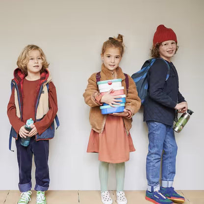 Kinderen met rugzakken en meerdere Mepal lunchboxen in handen, ideaal voor school en buitenshuis gebruik