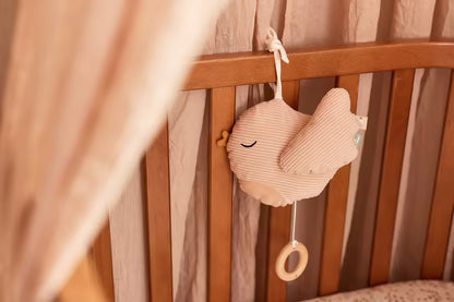 Jollein Muziekdoosje Lovely Birds in zachtroze vogelvorm, bevestigd aan een houten babybed als lieve muziekhanger.