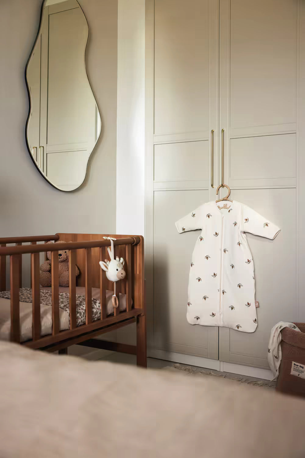 Jollein Muziekdoosje Giraffe bevestigd aan een houten ledikant in neutrale babykamer, stijlvol kraamcadeau en muziekdoosje baby.