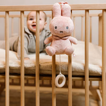 Muziekdoosje Nijntje in roze pluche met bloemmotief, baby speelt in ledikant met vrolijk muziekdoosje.