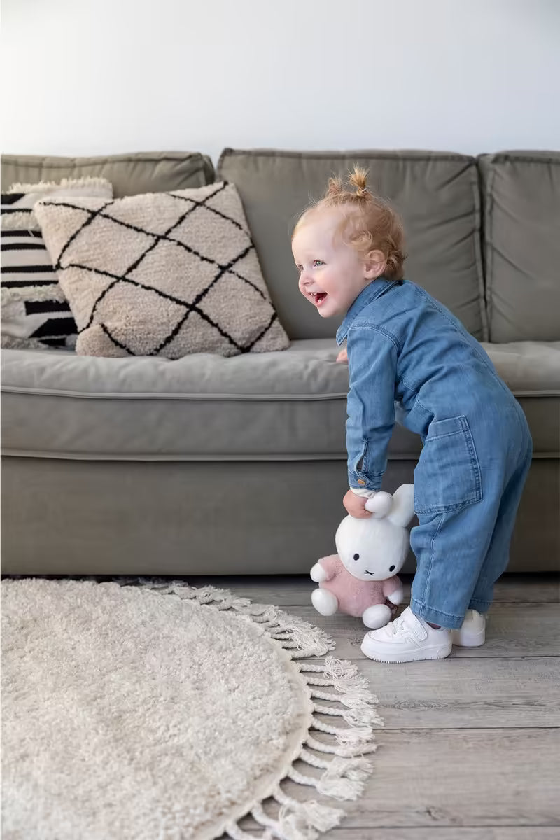 Nijntje knuffel Fluffy Pink 25cm vastgehouden door peuter in denim pakje, ideaal als baby cadeau of kraamcadeau.