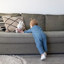 Kind speelt met Nijntje knuffel Fluffy Pink 25cm op groene bank, schattig kraamcadeau en sensorisch speelgoed.