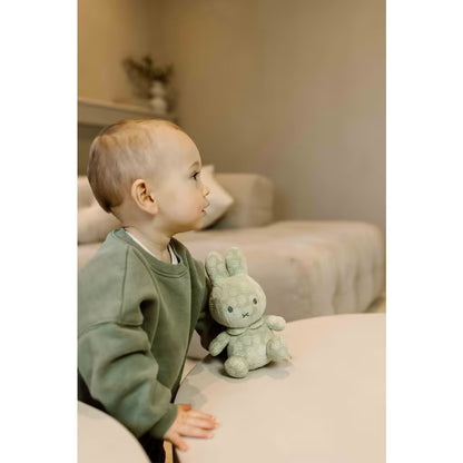 Peuter speelt met zachte groene Nijntje knuffel Green Flower 20cm, een veilig en knuffelbaar babyvriendje.