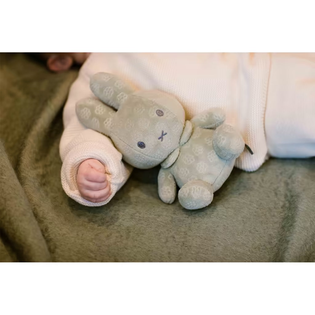 Baby slaapt rustig naast groene Nijntje knuffel Green Flower 20cm, een troostend knuffelvriendje voor kleintjes.