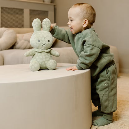 Lachend kind bewondert Nijntje Knuffel Groot Green Flower 30cm, pluche knuffel en ideaal als baby cadeau of kraamcadeau.