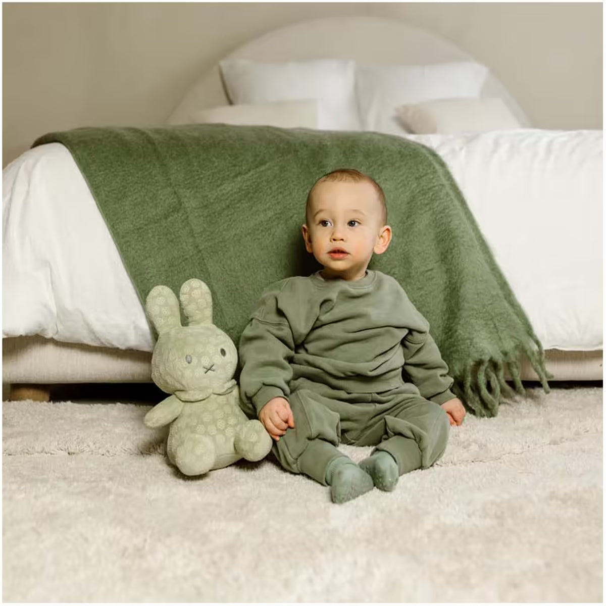 Kind zit in slaapkamer naast Nijntje Knuffel Groot Green Flower 30cm, een knusse pluche knuffel en leuk kraamcadeau.