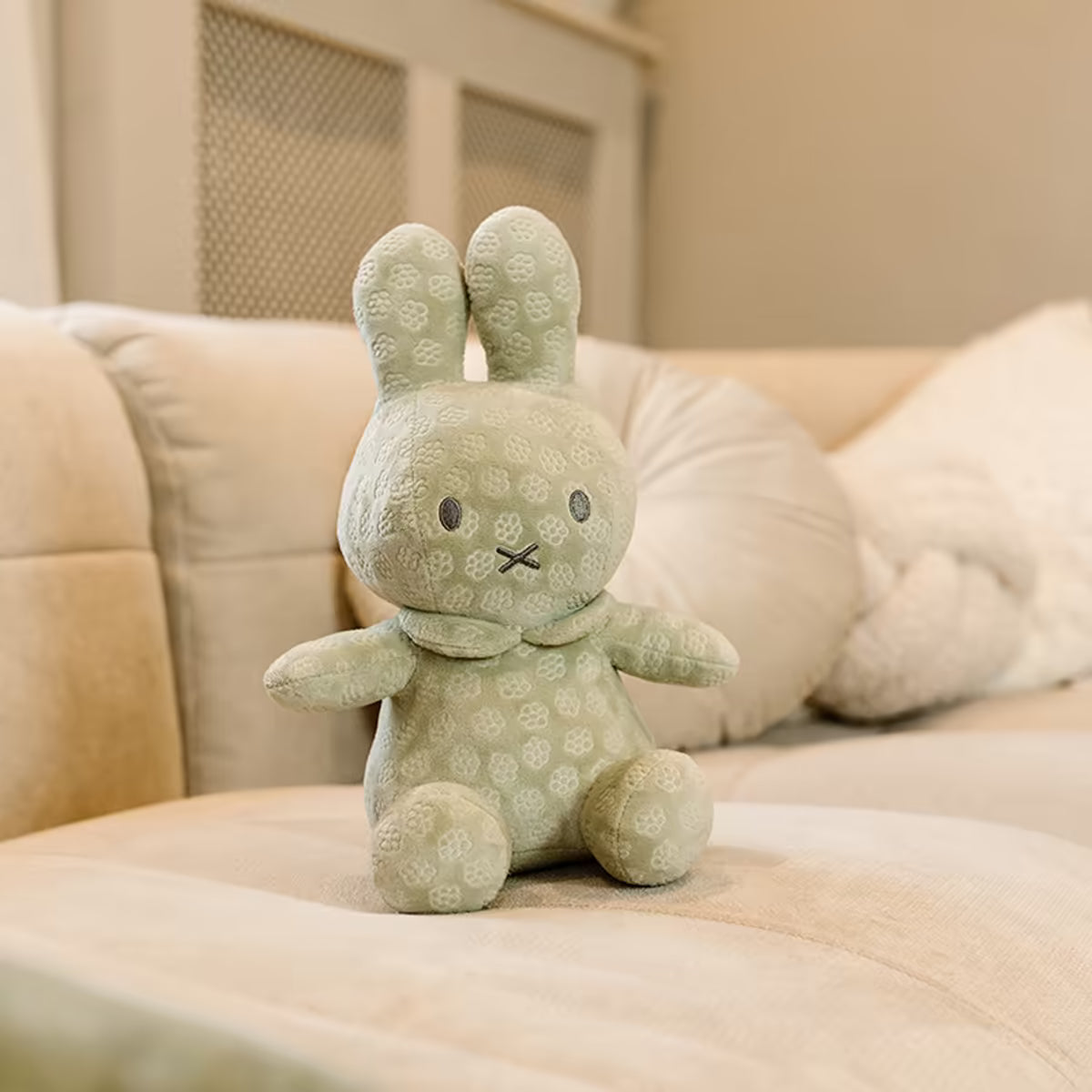 Nijntje Knuffel Groot Green Flower 30cm zacht pluche knuffelkonijn, sfeervol geplaatst op een beige bank in woonkamer.