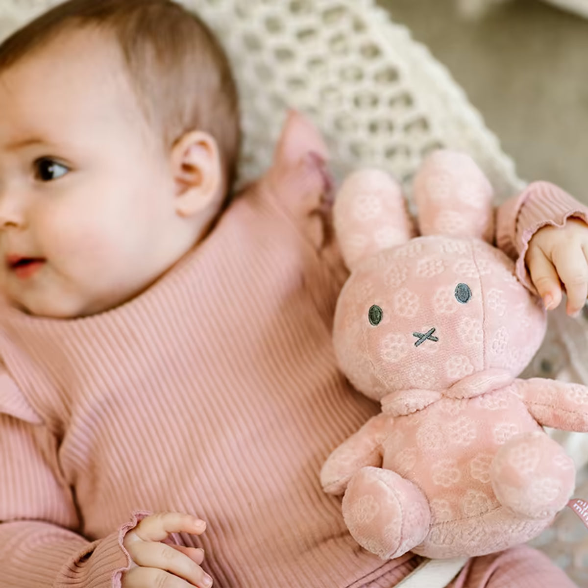 Baby ligt met Nijntje knuffel Pink Flower 20cm, een zachte pluche knuffel en sensorisch speelgoed.