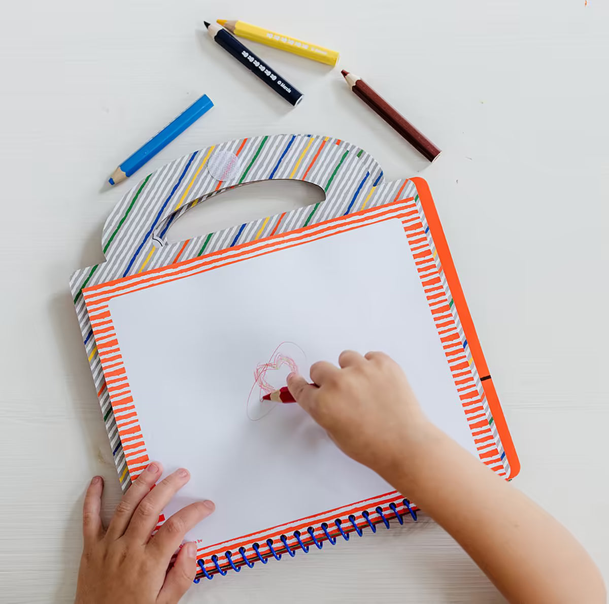 Peuter tekent met rood potlood in Nijntje Knutselboek, speelse activiteit en Doeboek vol knutsel ideeën.