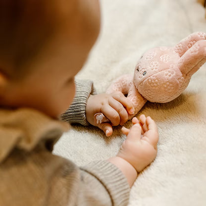 Baby speelt op zachte deken met roze Nijntje Rammelaar Pink Flower, ideaal baby speelgoed en lief kraamcadeau.