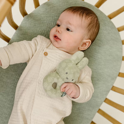 Liggende baby houdt Nijntje Rammelaar Green Flower vast, schattig educatief speelgoed en leuk kraamcadeau idee.