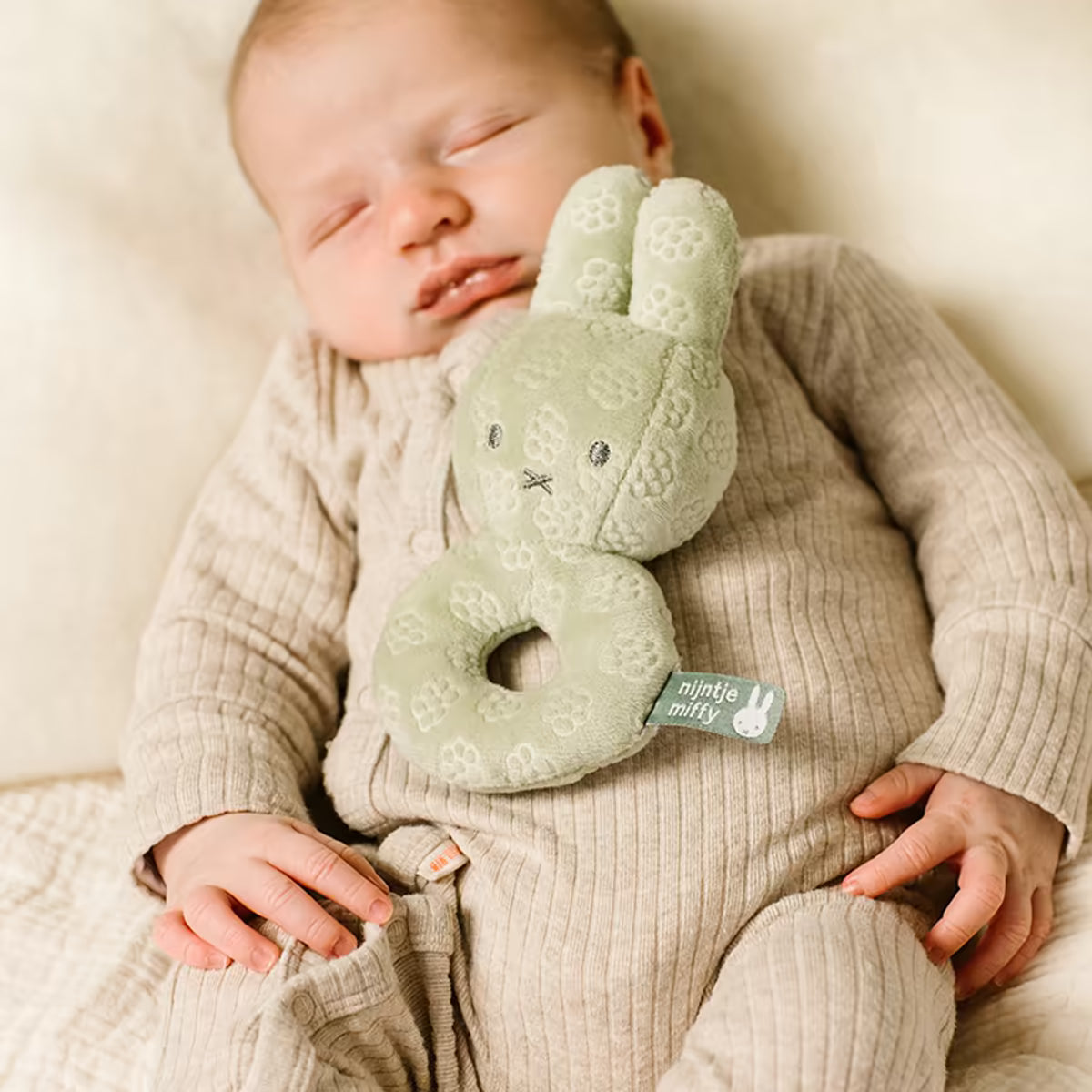 Slapende baby met Nijntje Rammelaar Green Flower op borst, prachtig kraamcadeau en zacht baby speelgoed.