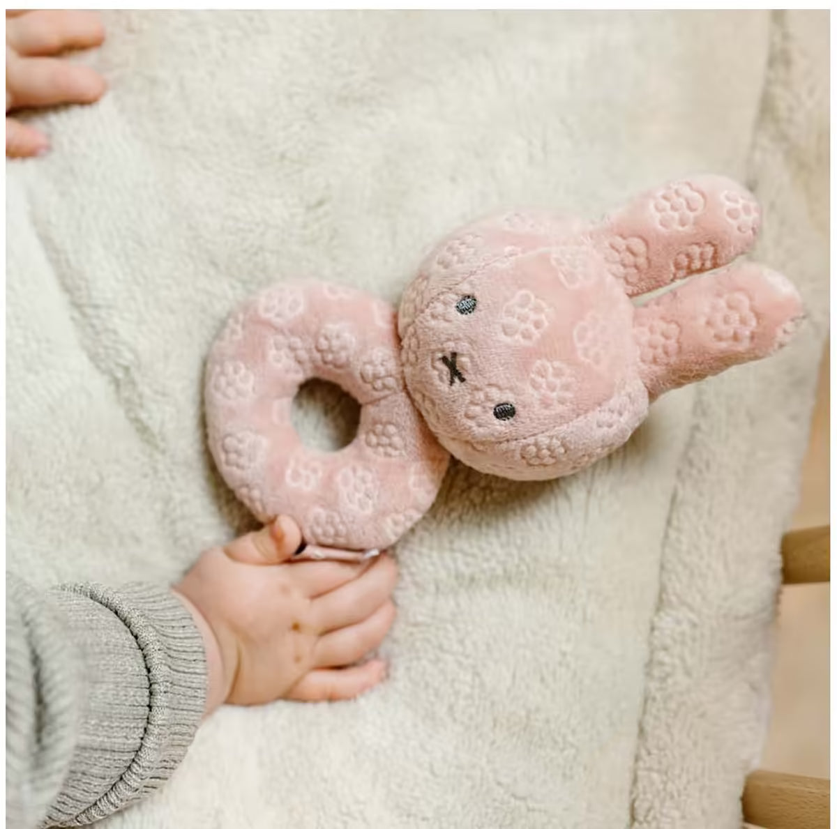 Detailfoto van babyhand met Nijntje Rammelaar Pink Flower, zacht sensorisch speelgoed en schattig baby cadeau.