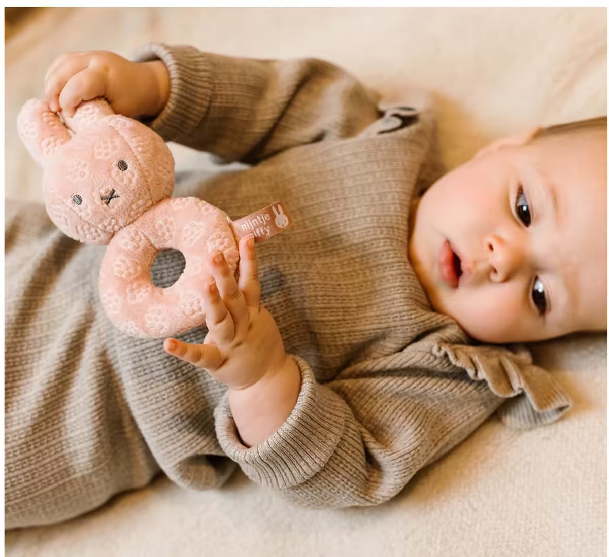Baby ontdekt zachte Nijntje Rammelaar Pink Flower, perfect sensorisch speelgoed en leuk baby cadeau voor kleintjes.