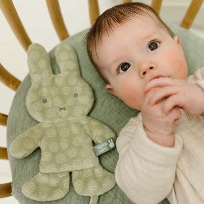Baby kijkt vrolijk naast het Nijntje Speendoekje green flower, zacht knuffeldoekje en perfect kraamcadeau.
