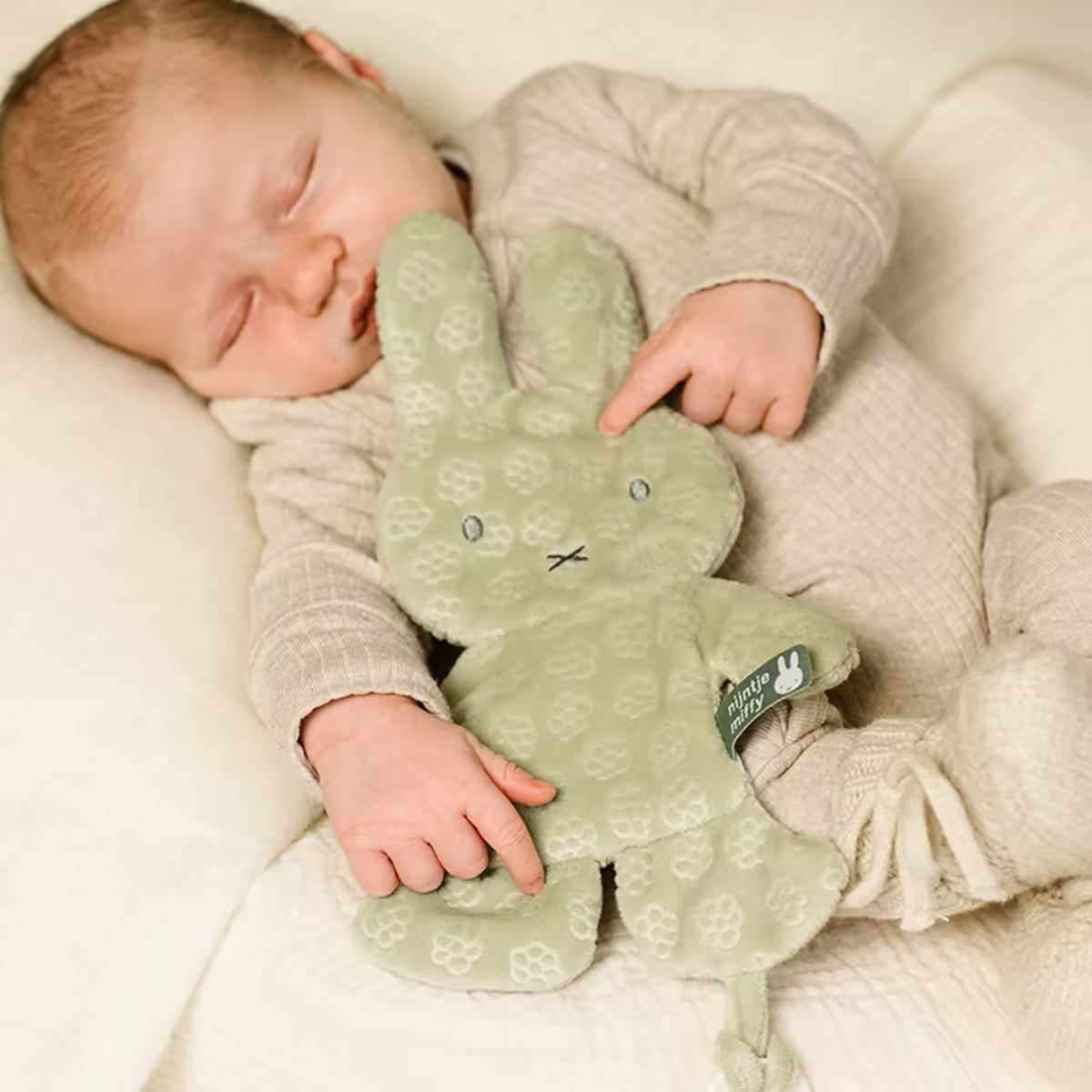 Slapende baby knuffelt met het Nijntje Speendoekje green flower, een zacht knuffeldoekje en prachtig kraamcadeau.