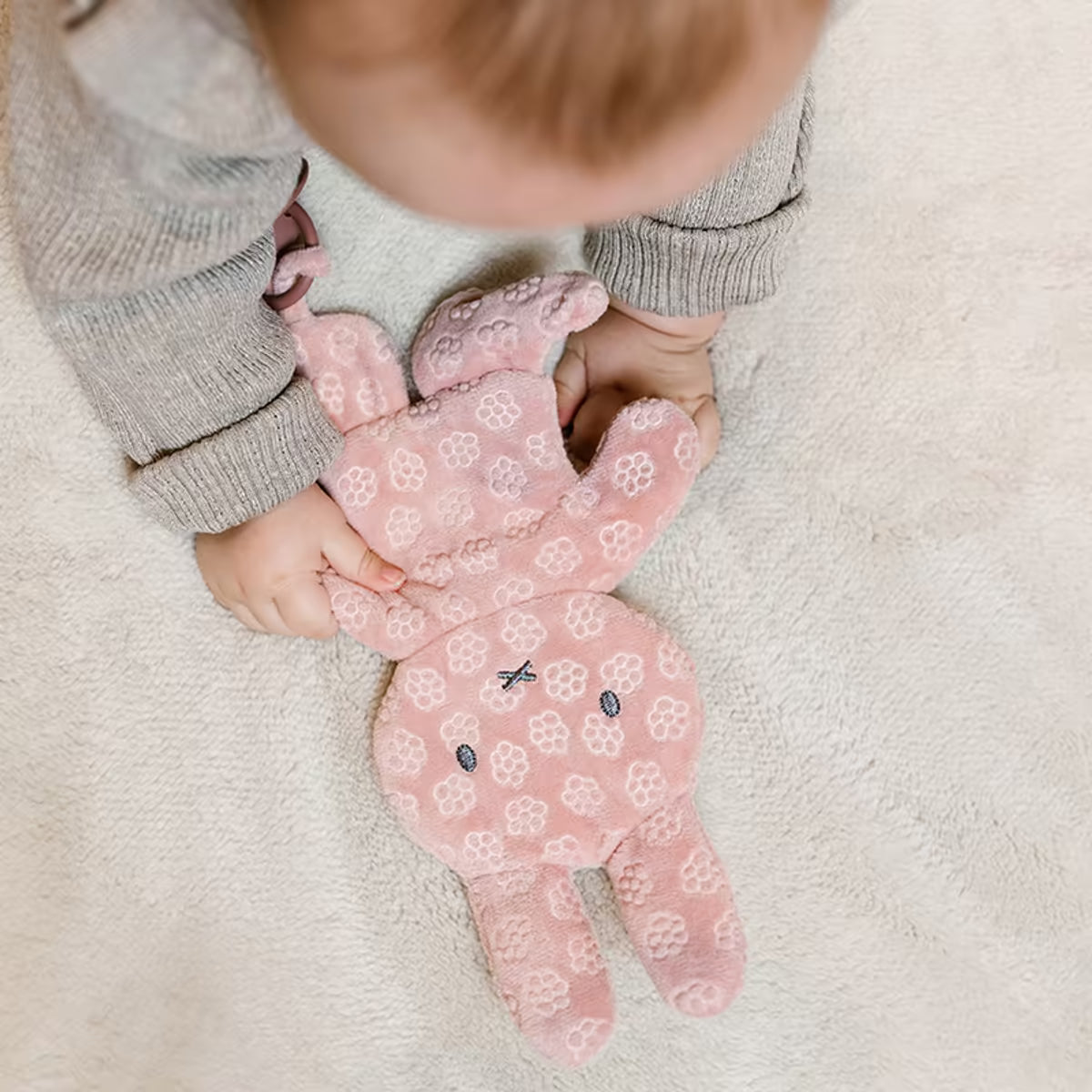 Detailfoto van babyhandjes die Nijntje Speendoekje Pink Flower vasthouden, ideaal knuffeldoekje als baby cadeau.