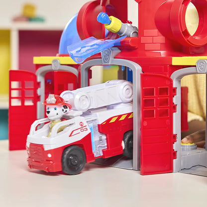 Marshall rijdt brandweerauto uit Paw Patrol Fire Rescue Fire station speelgoedset met rode deuren en blauwe details.