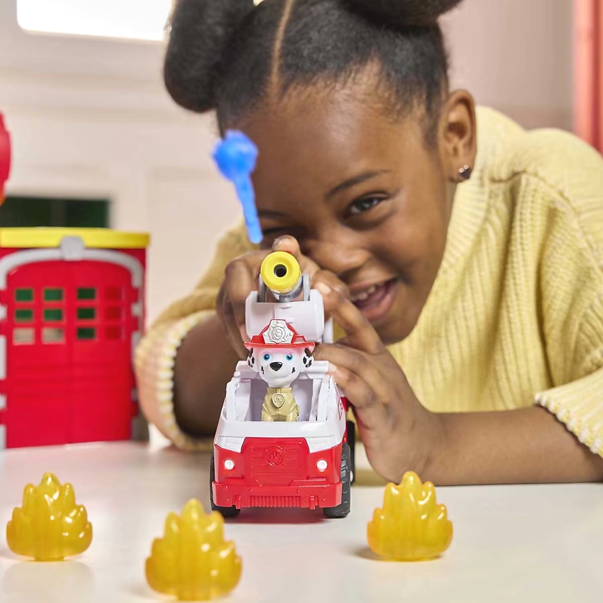 Kind schiet met waterkanon van Marshall uit Paw Patrol Fire Rescue Fire station speelset met vlammen.