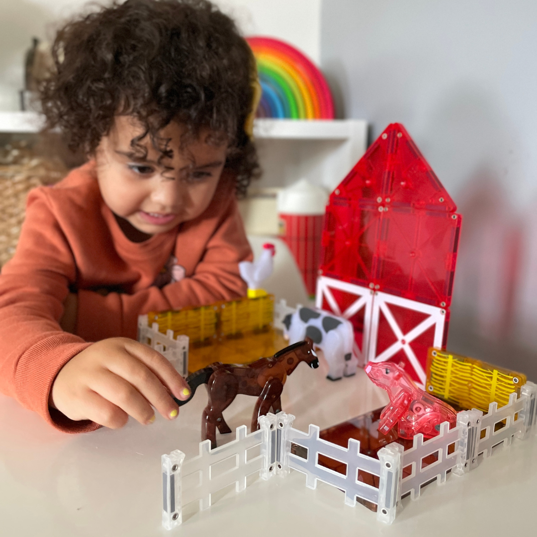 Peuter speelt met magnetic magna tiles boerderij en farm animals in kleurrijke speelruimte
