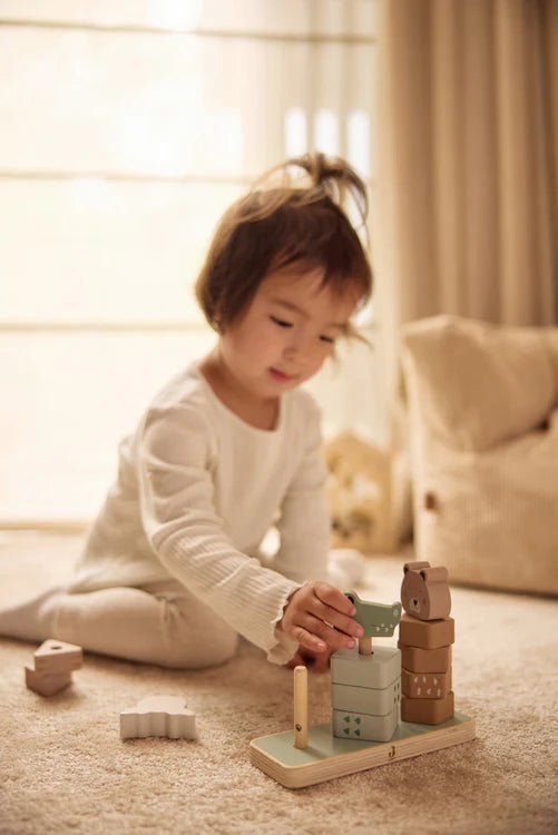 Peuter speelt op vloerkleed met houten stapeltoren van Jollein met jungle dieren, educatief Montessori speelgoed voor binnen.