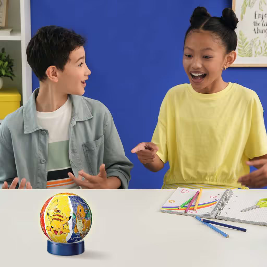 Twee kinderen spelen enthousiast met Pokémon 3D puzzel nachtlampje van Ravensburger, kleurrijk en leuk.