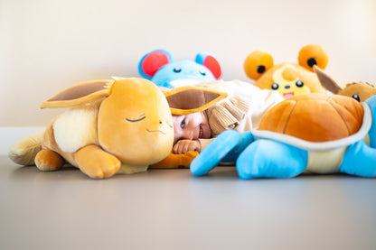 Knuffels met Eevee Pokemon knuffel vooraan en kind dat tussen zachte Pokemon speelgoed ligt