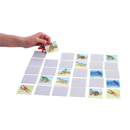 Hand draait Ravensburger dinosaurus memory kaart om tijdens spel, kindvriendelijk en leerzaam voor peuters.