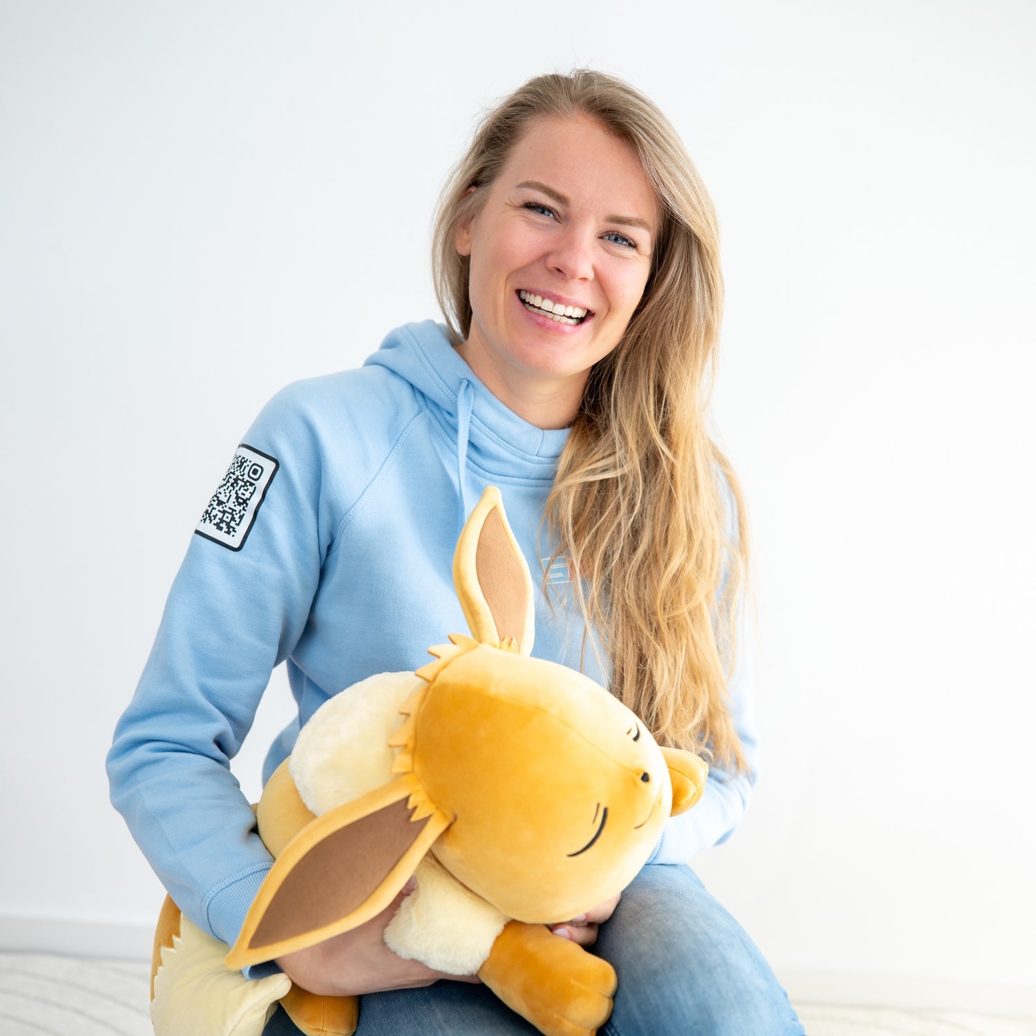 Eigenaar Ruby lacht met Eevee Pokemon knuffel, portretfoto met witte achtergrond en hoodie