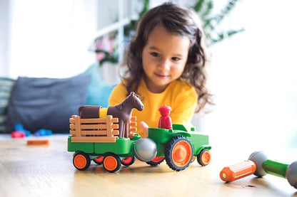 Meisje speelt met SmartMax My First Tractor SMX 222 STEM speelgoed, groene tractor met paard en boer