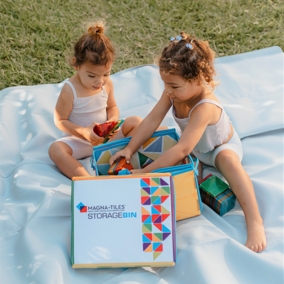 Speelkleed buitenshuis met twee kinderen die magnetische Magna Tiles bouwen op blauwe mat