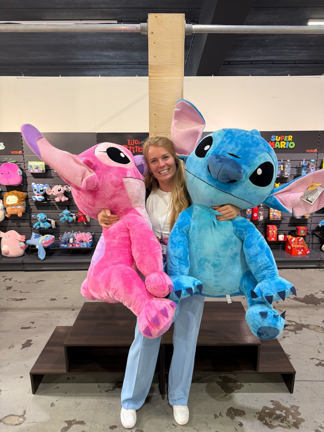 Sproutz co founder Ruby lacht in camera op een speelgoed beurs en heeft 2 knuffels van Stitch vast.