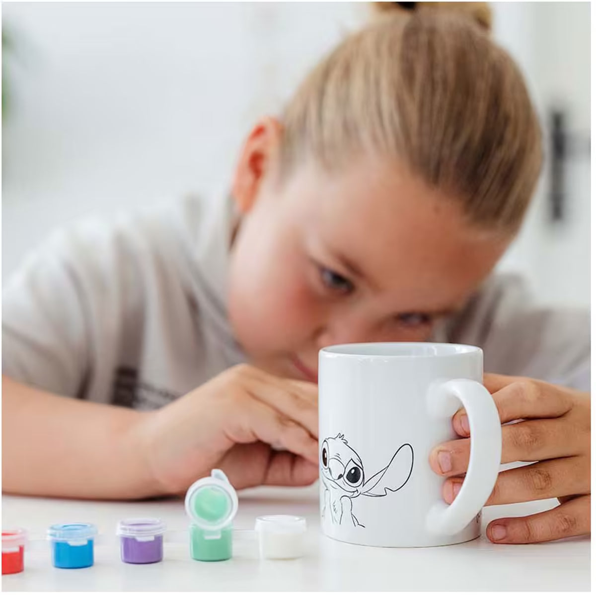 Kind schildert eigen Disney Stitch mok met Totum set, vrolijk knutsel idee en activiteit om gezellig te knutselen met peuters.