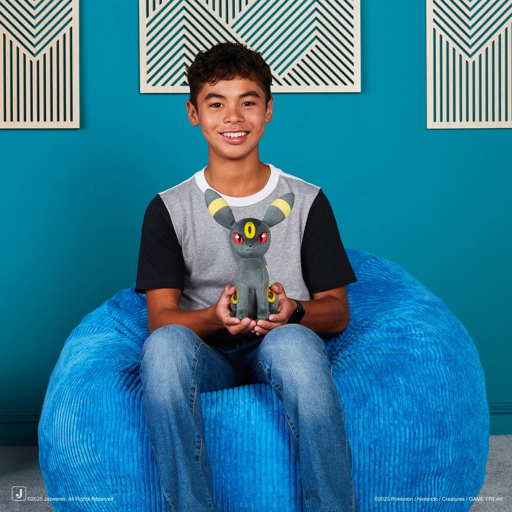 Umbreon Pokémon knuffel vastgehouden door kind in speelse setting, zachte Pokémon knuffel van Jazwares voor jonge fans.