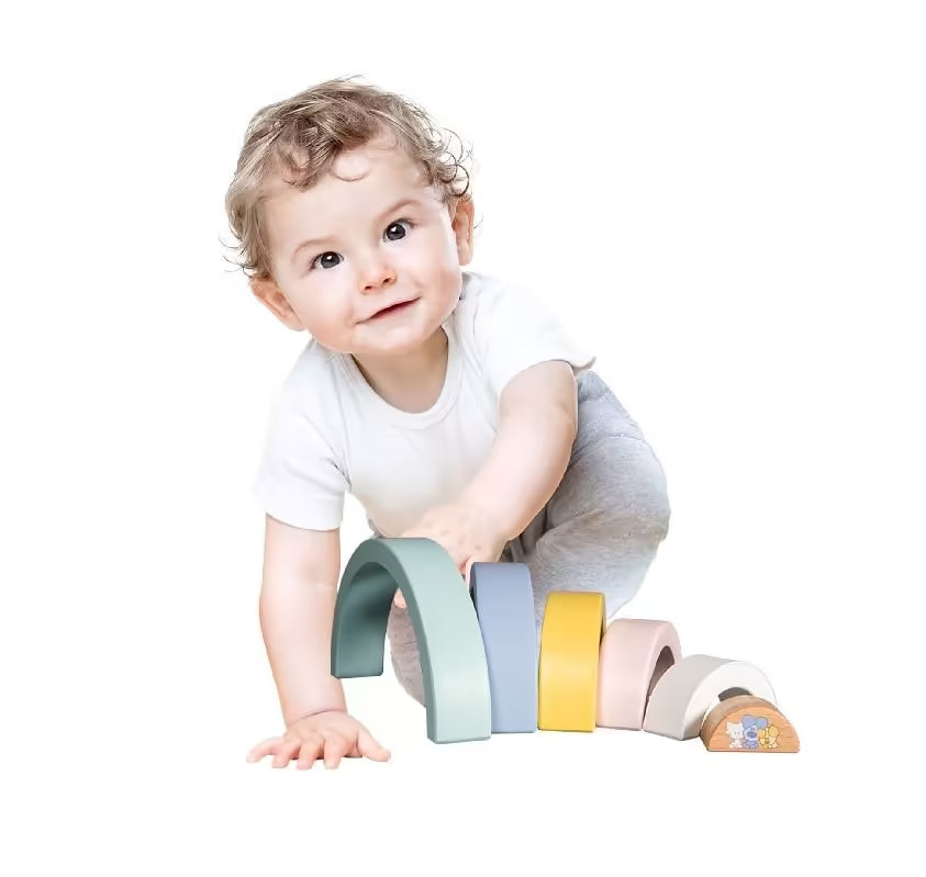 Baby speelt op de grond met Woezel en Pip Baby Regenboog, een houten speelgoed set met zes kleurrijke bogen.