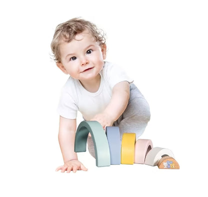 Baby speelt op de grond met Woezel en Pip Baby Regenboog, een houten speelgoed set met zes kleurrijke bogen.